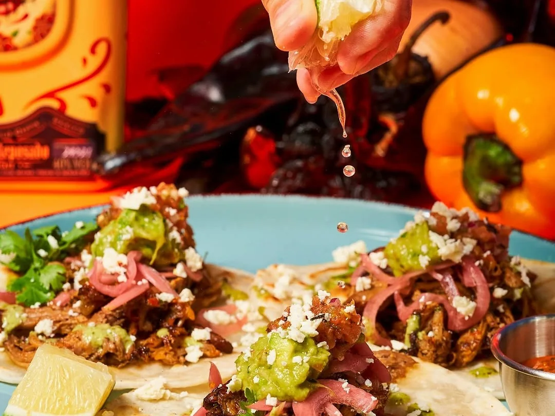 A colorful MamaMita taco dish with orange and red background details.