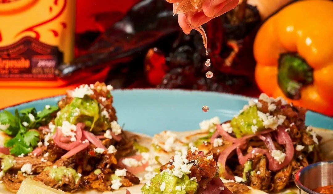 A colorful MamaMita taco dish with orange and red background details.